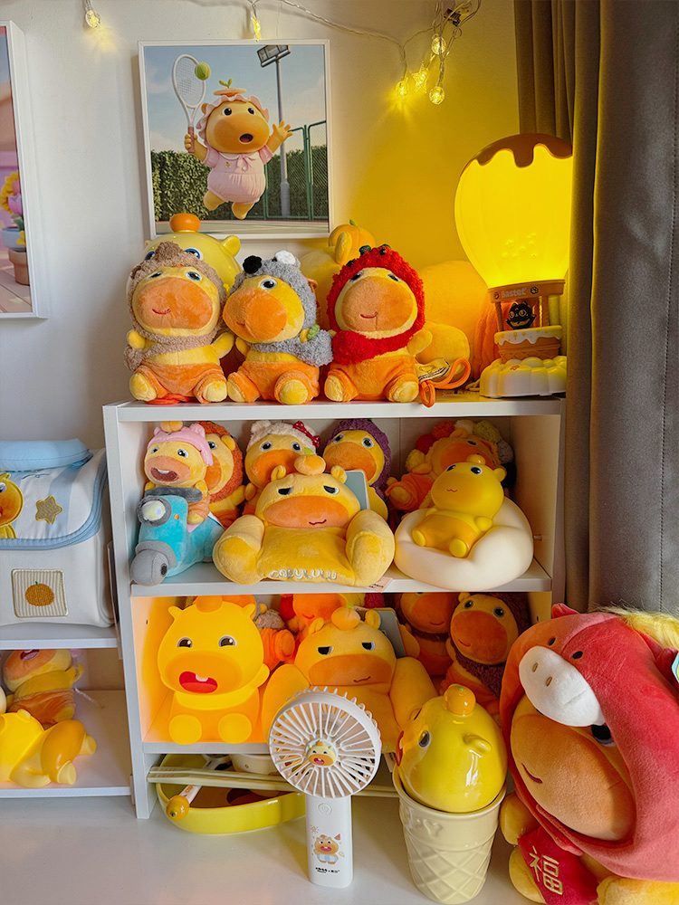 A warm studio shelf filled with Lulu figures, plush toys, and a glowing character lamp