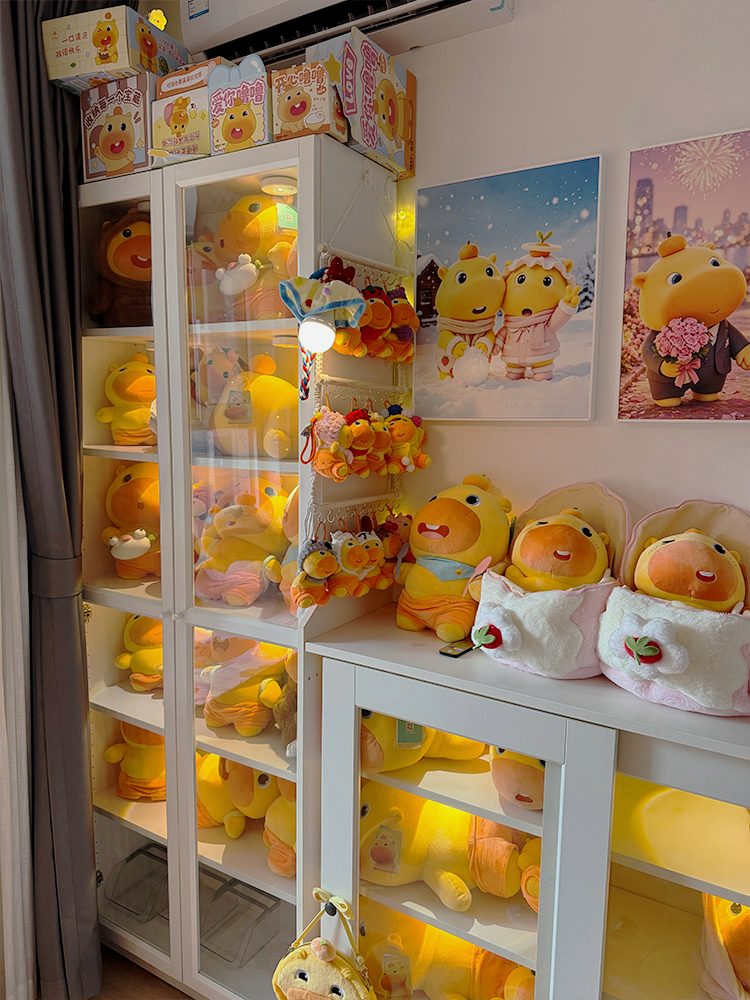 A CapyLulumi display cabinet and cozy Lulu plush corner with framed artwork